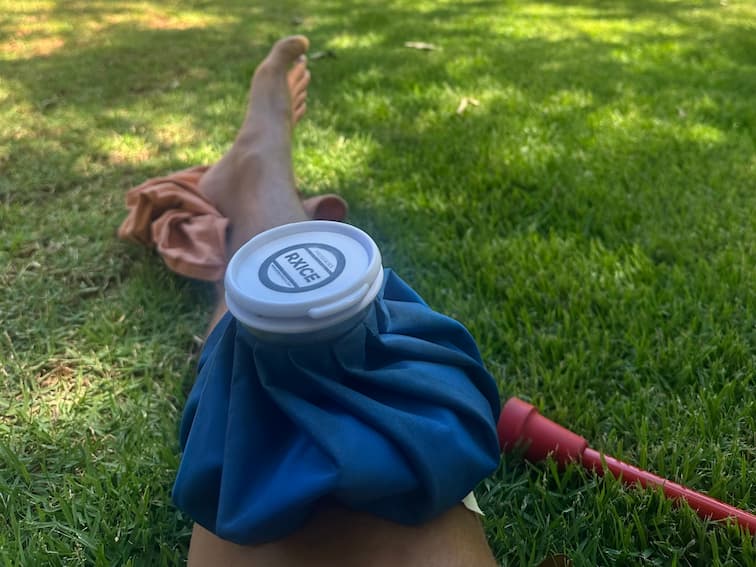 Blue fabric ice bag strapped to the knee for portable cold therapy and swelling control